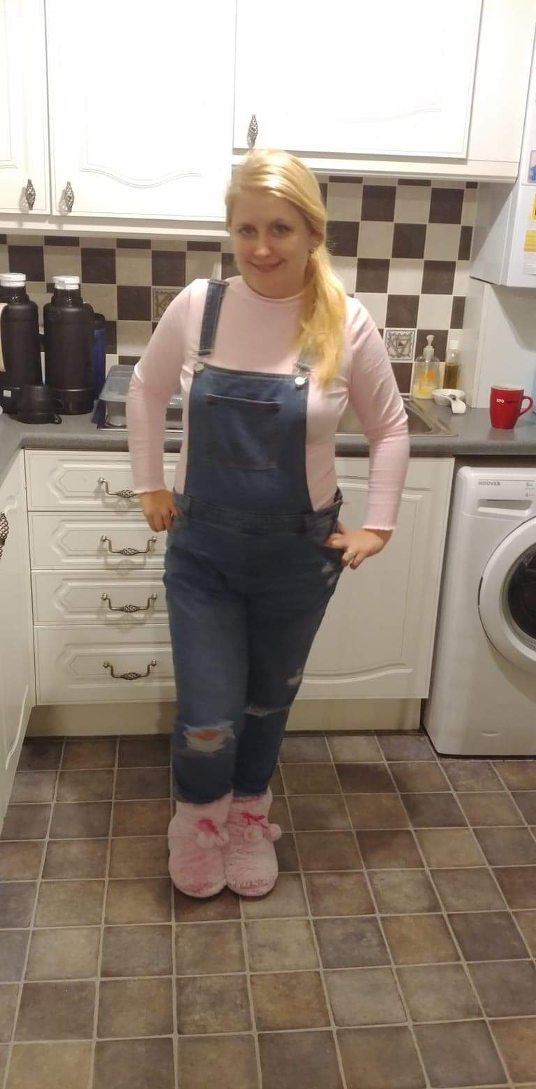 Blonde woman wearing pink jumper and blue denim dungarees for outfit of the day post. 