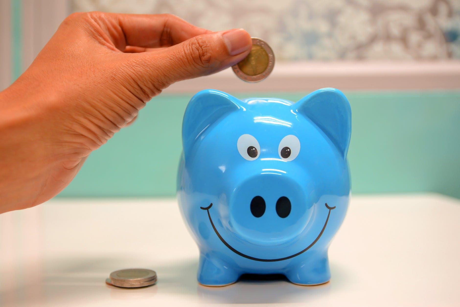 person putting coin in a piggy bank for 8 things I'm letting go of post