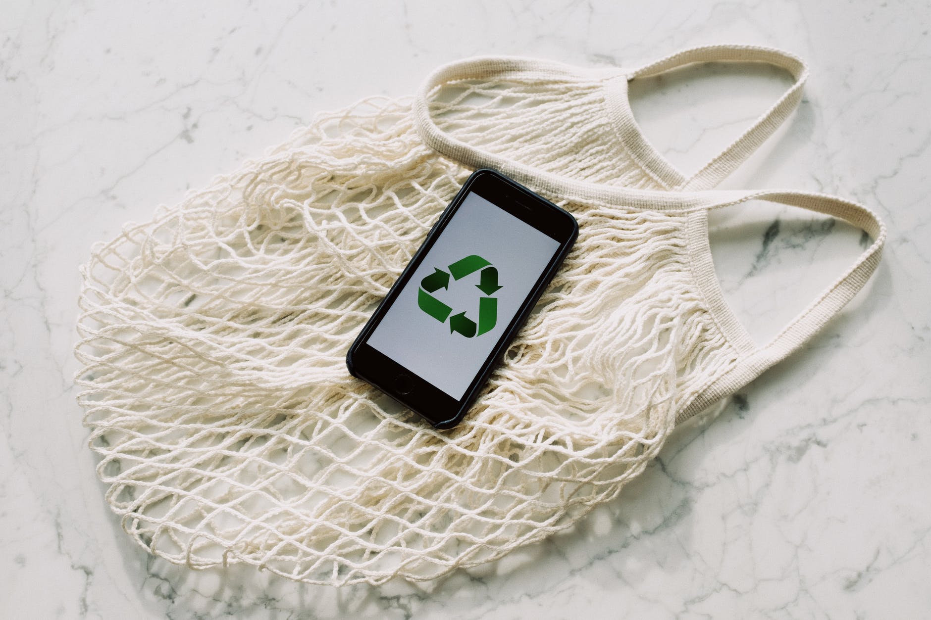 Ways to be more sustainable this Christmas - mobile phone with green recycling sign and mesh bag